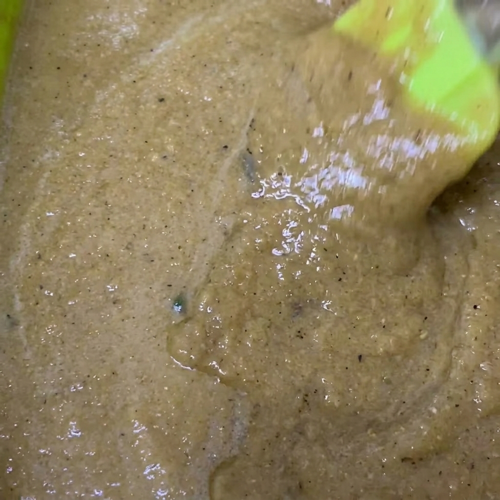 Una ciotola verde contenente la marinata frullata con laggiunta di salsa di soia e pepe nero.