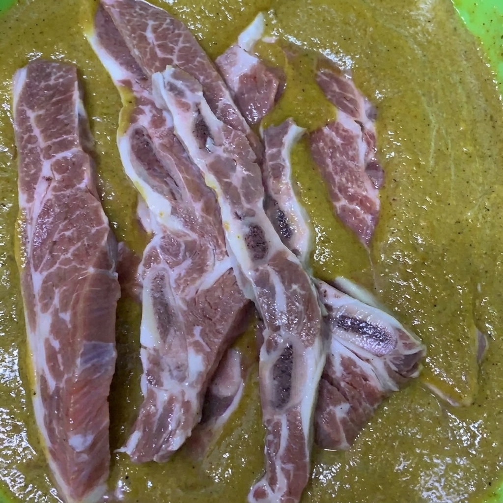 Costolette di manzo immerse e mescolate in una ciotola piena della marinata coreana preparata.