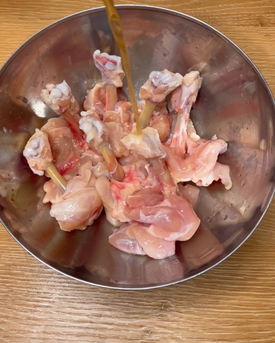 Cosce di pollo condite in una ciotola di metallo con vino di riso, spezie e uovo.