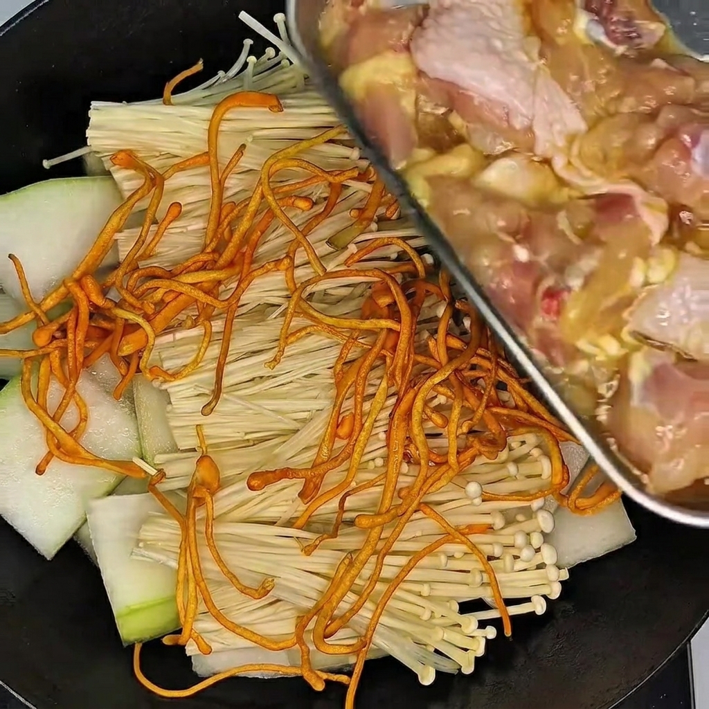 Una mano con guanto mescola e massaggia le cosce di pollo in una ciotola con la marinata.