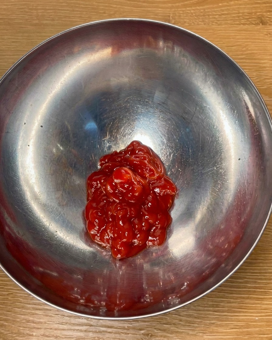 Ketchup al pomodoro e condimenti mescolati in una ciotola di metallo per creare una salsa saporita.