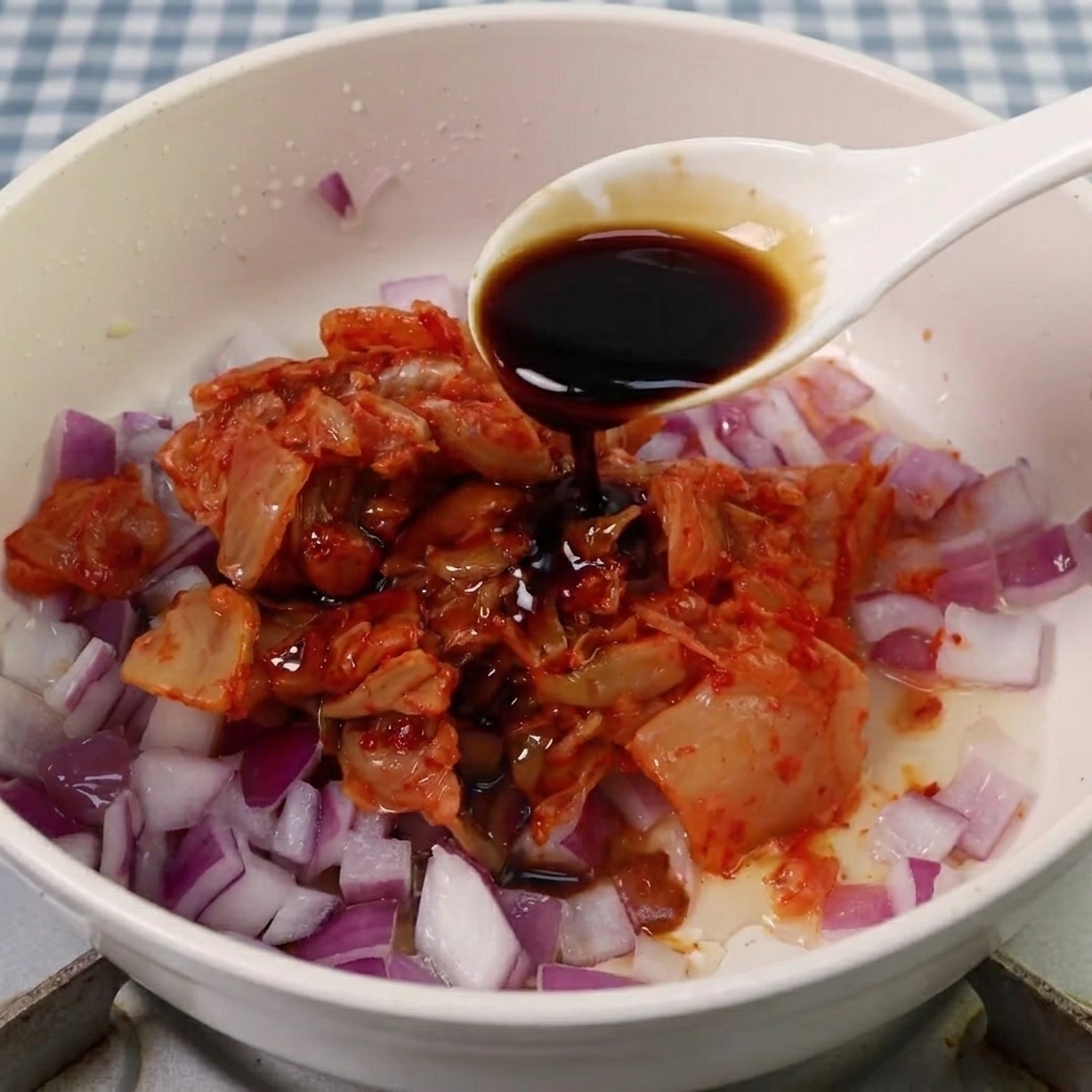 Salsa di soia, zucchero e pasta piccante coreana aggiunti al composto di kimchi e cipolla.