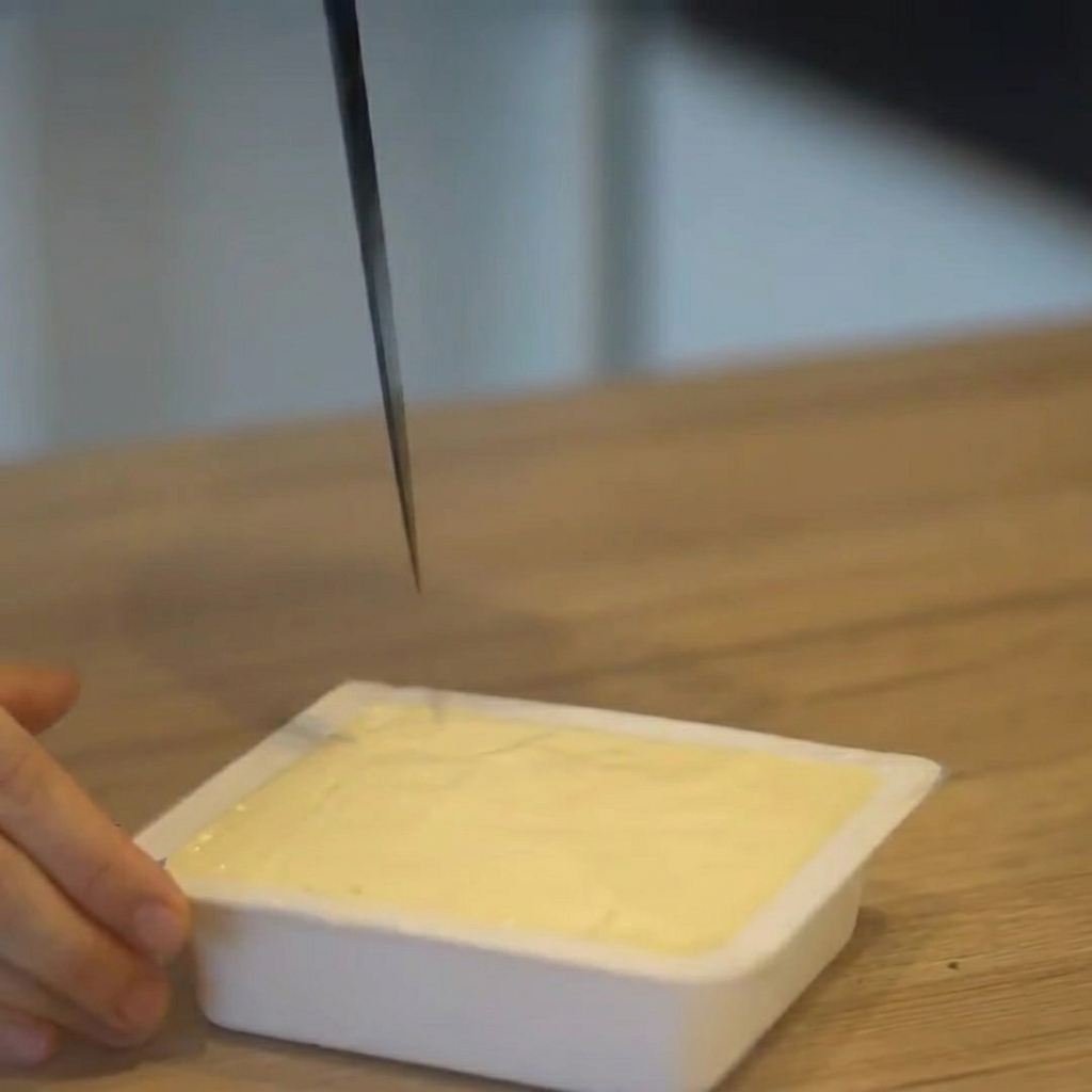 Tofu tagliato a cubetti mentre è ancora nella sua confezione di plastica.