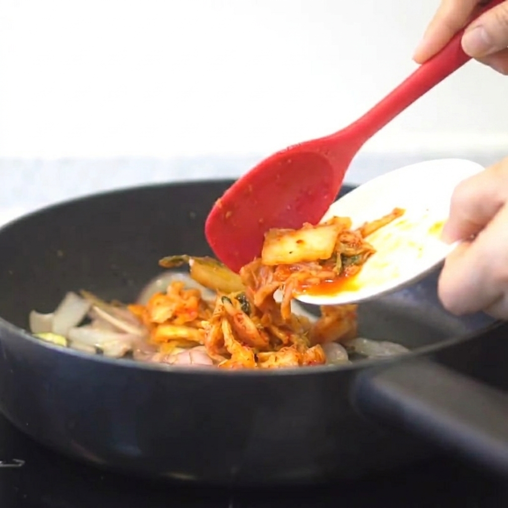 Kimchi aggiunto in padella con le cipolle e laglio saltati.