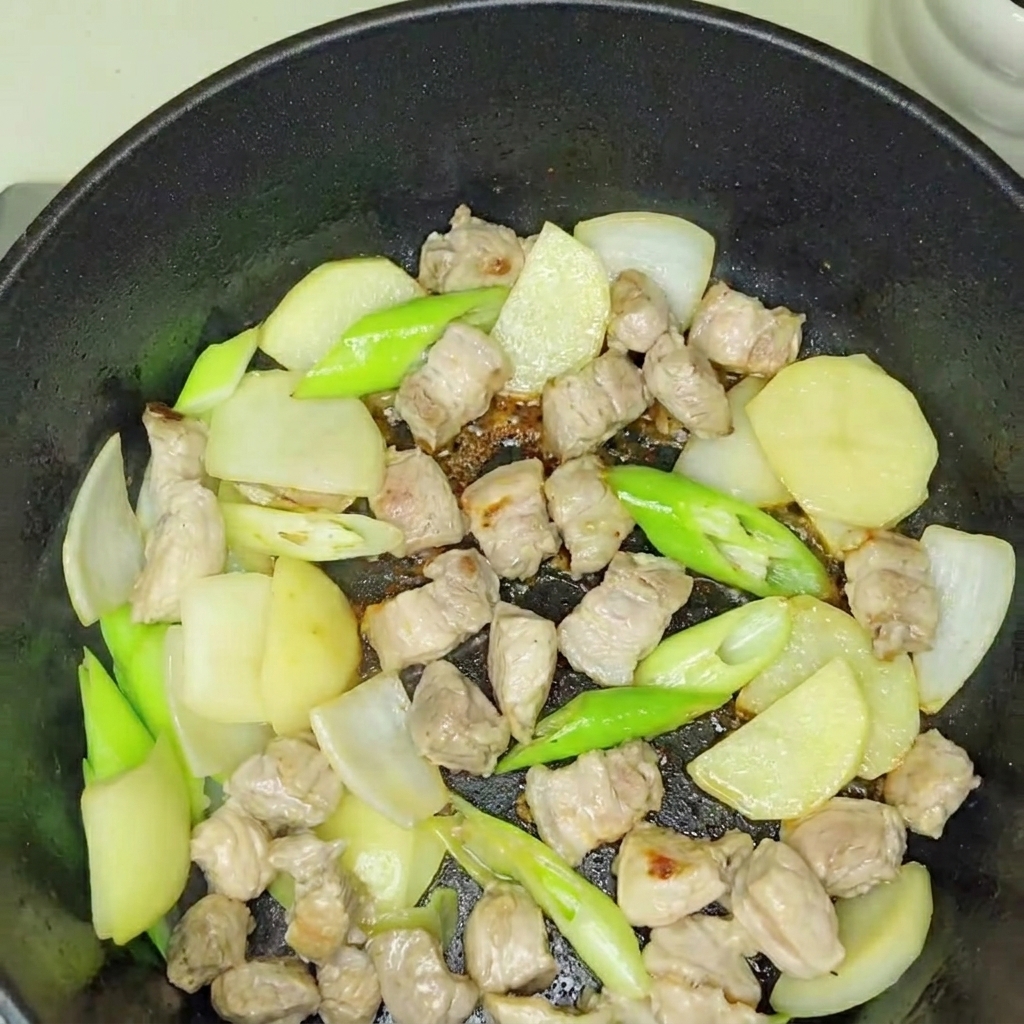 Kimchi aggiunto nella pentola insieme alla base di maiale e cipolla.