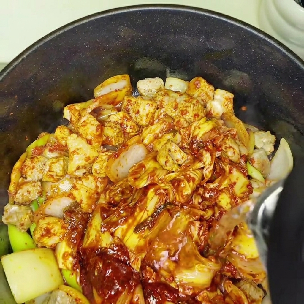 Acqua versata nella pentola con il composto di kimchi e maiale per iniziare la cottura.