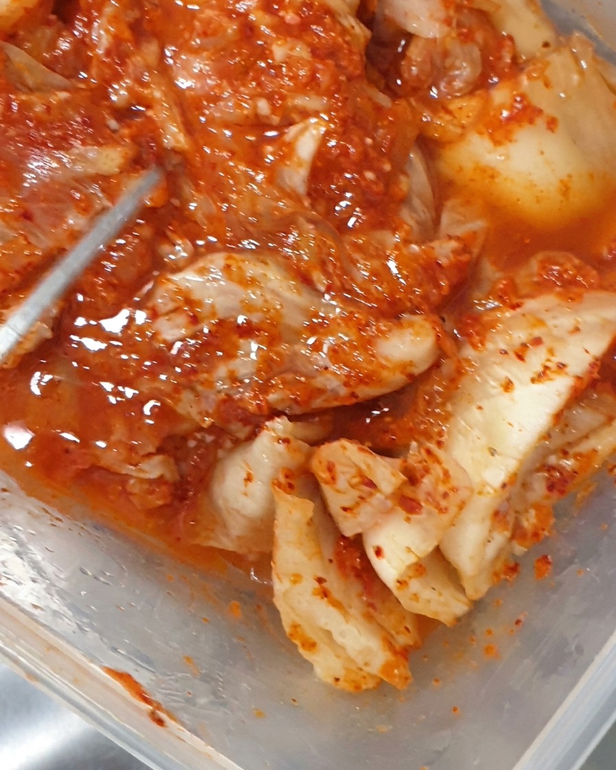 Pinze che mettono pezzi di kimchi fermentato in una pentola che bolle.