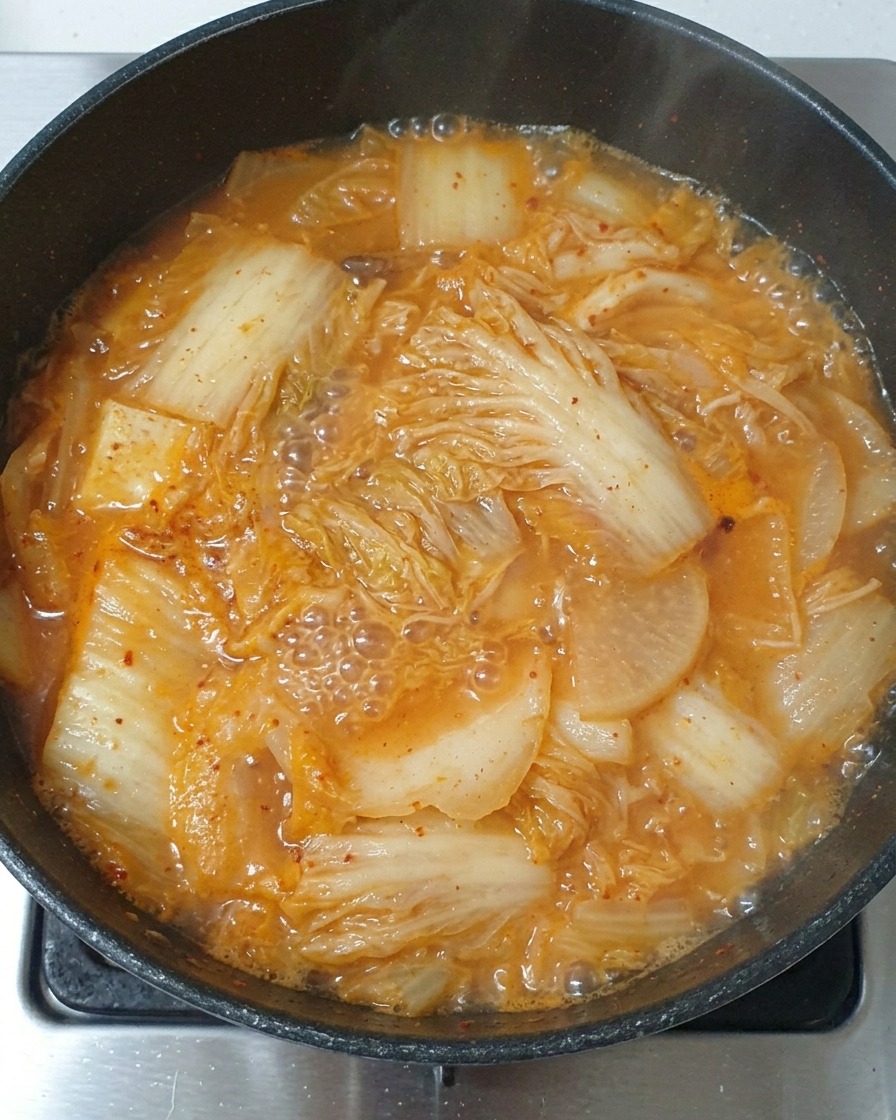Un cucchiaio di salsa di soia leggera versato nello stufato di kimchi in ebollizione.