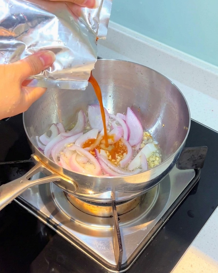 Kimchi versato nella pentola e mescolato con cipolle e aglio.