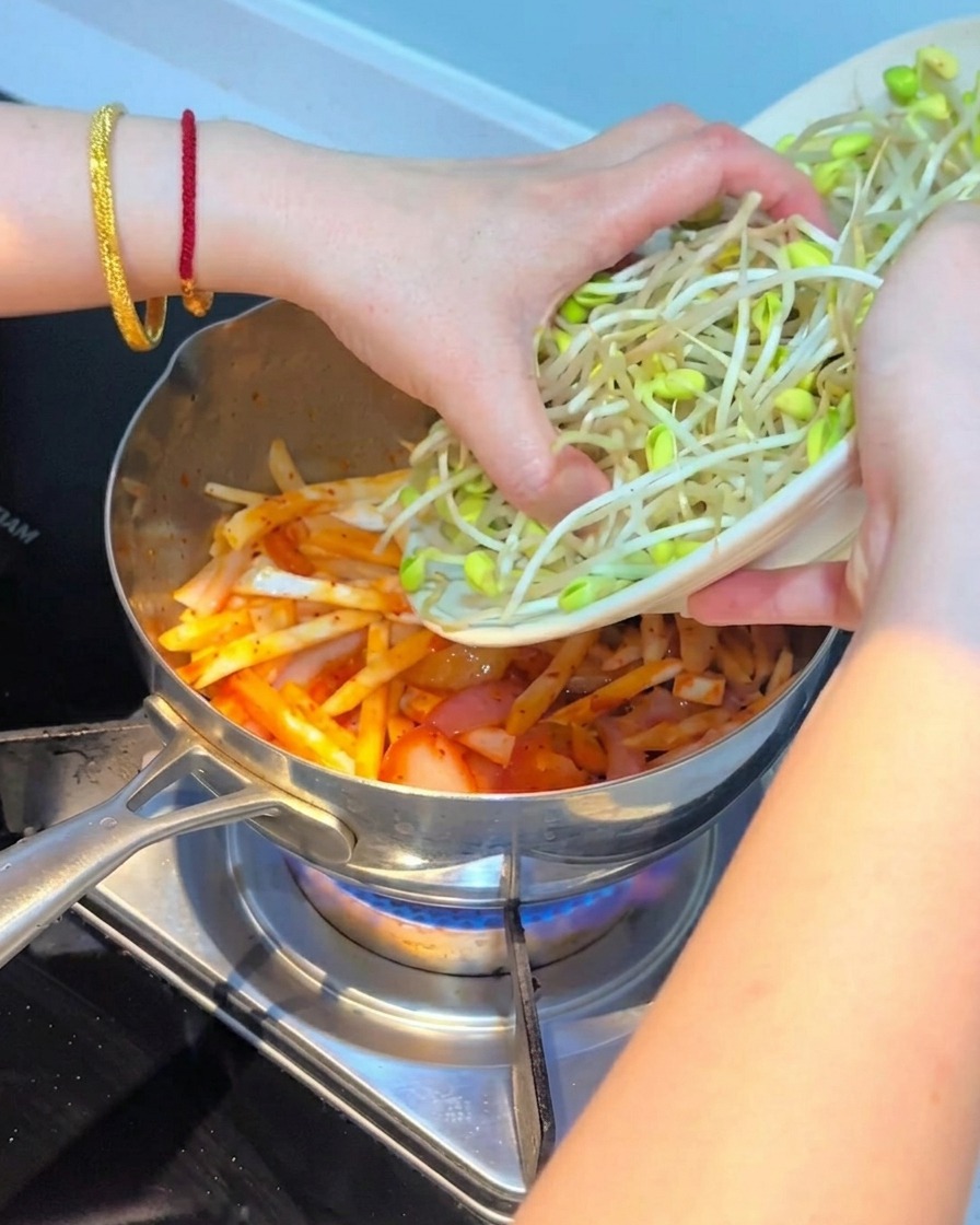 Germogli di soia freschi disposti sopra il composto di kimchi e funghi.