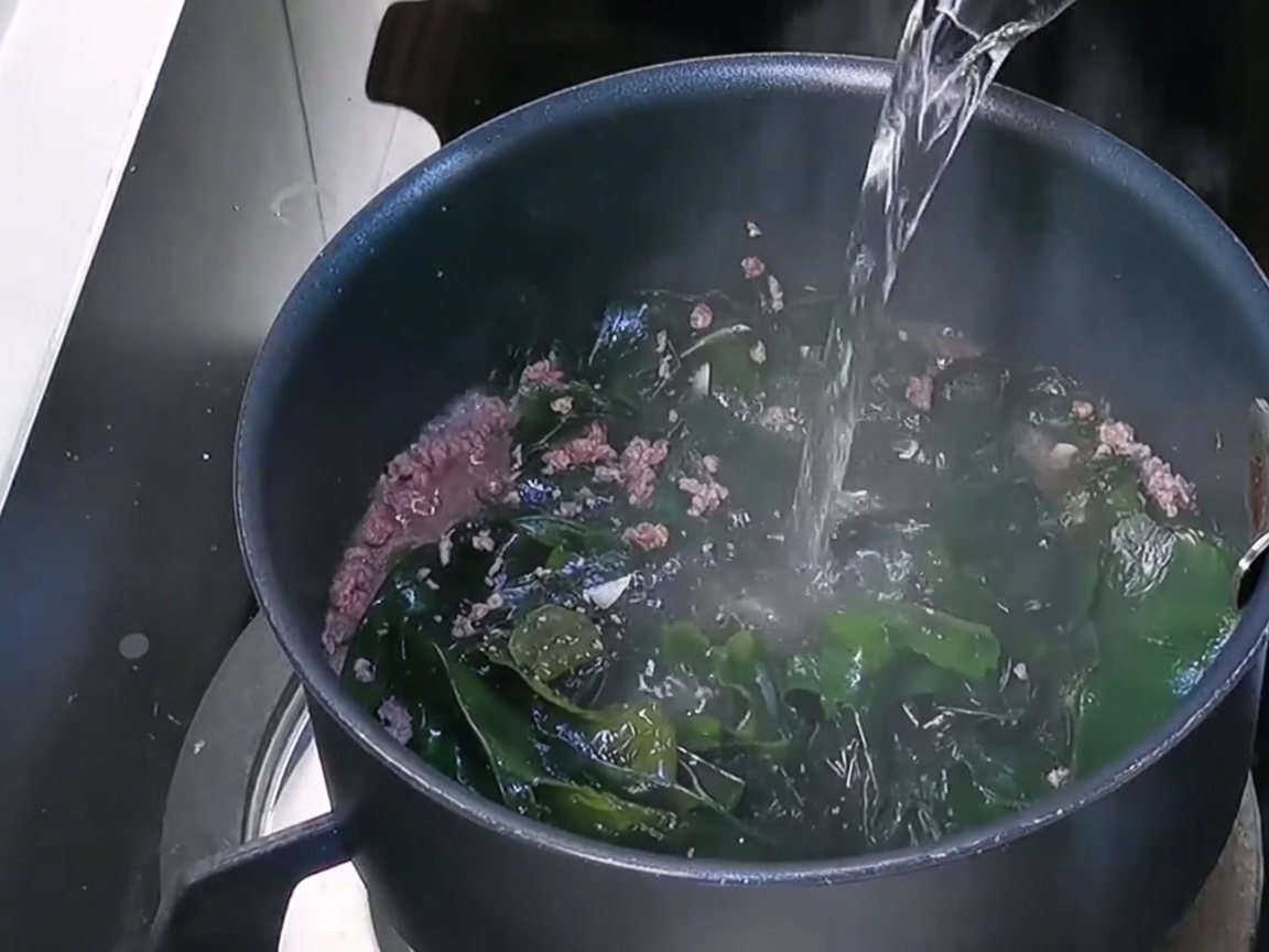 Acqua fresca versata nella pentola sulla base di manzo e wakame.