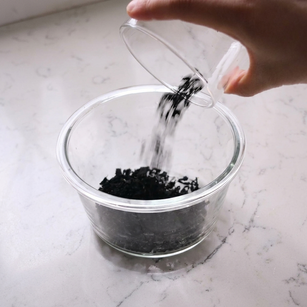 Alga wakame secca in ammollo in una ciotola di vetro con acqua.