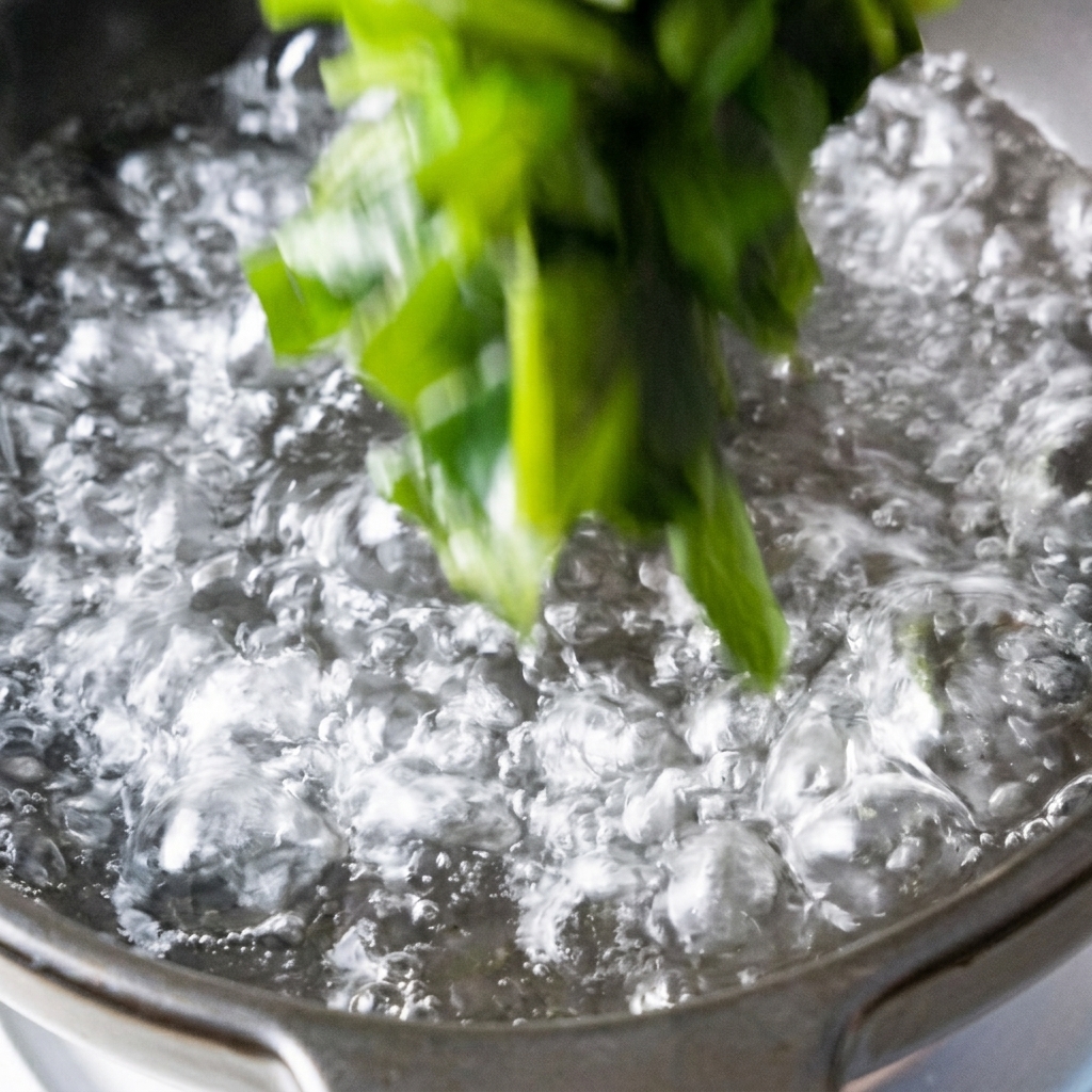 Wakame e cubetti di tofu aggiunti in una pentola di acqua bollente.