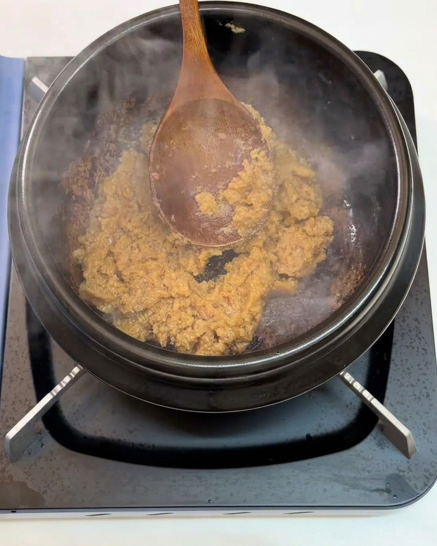 Aglio tritato aggiunto alla pasta di soia che soffrigge nella pentola.
