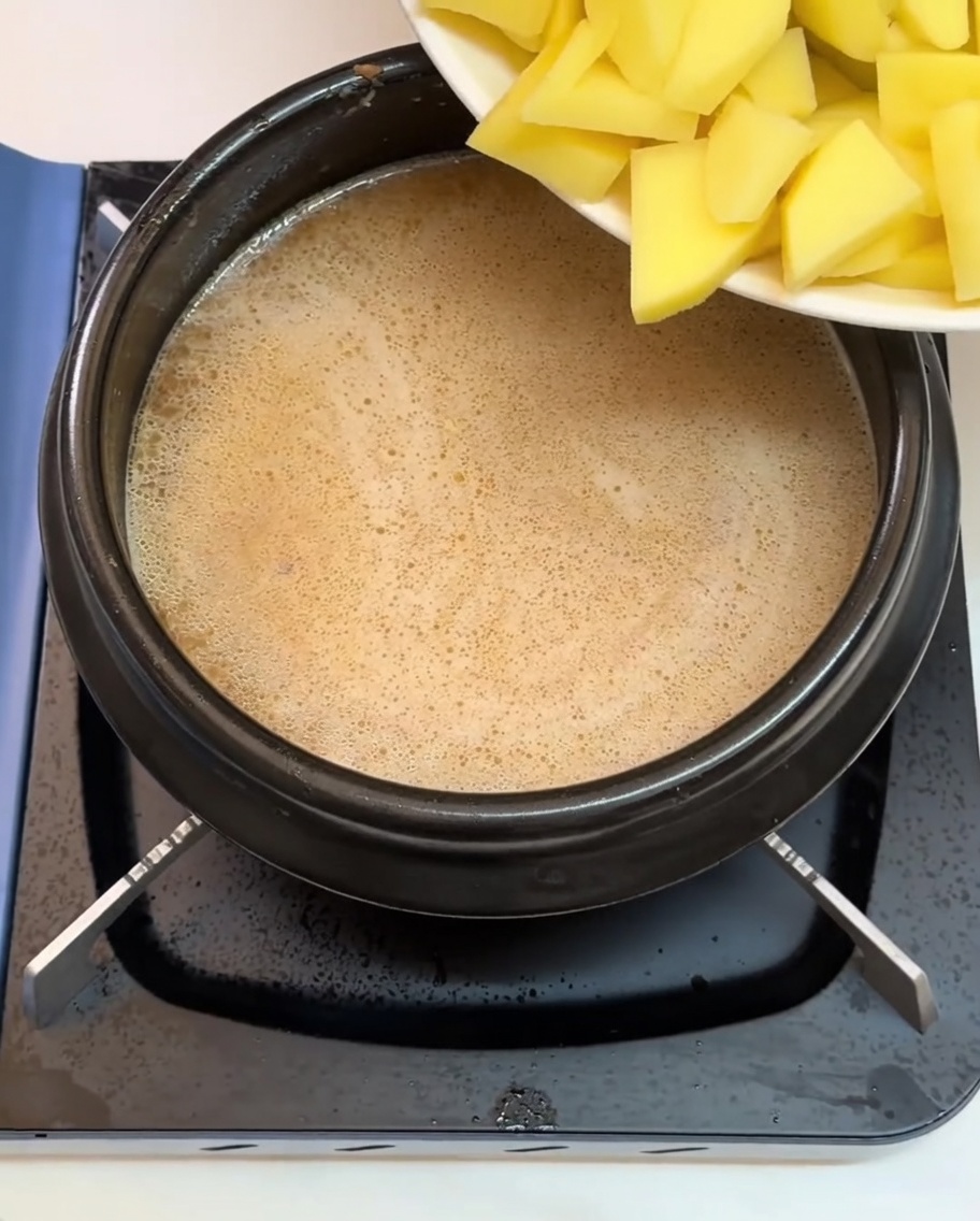 Patate e altri ingredienti tritati aggiunti nel brodo bollente.