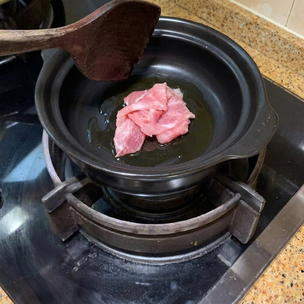 Fette di maiale saltate in un tegame di terracotta caldo con olio.
