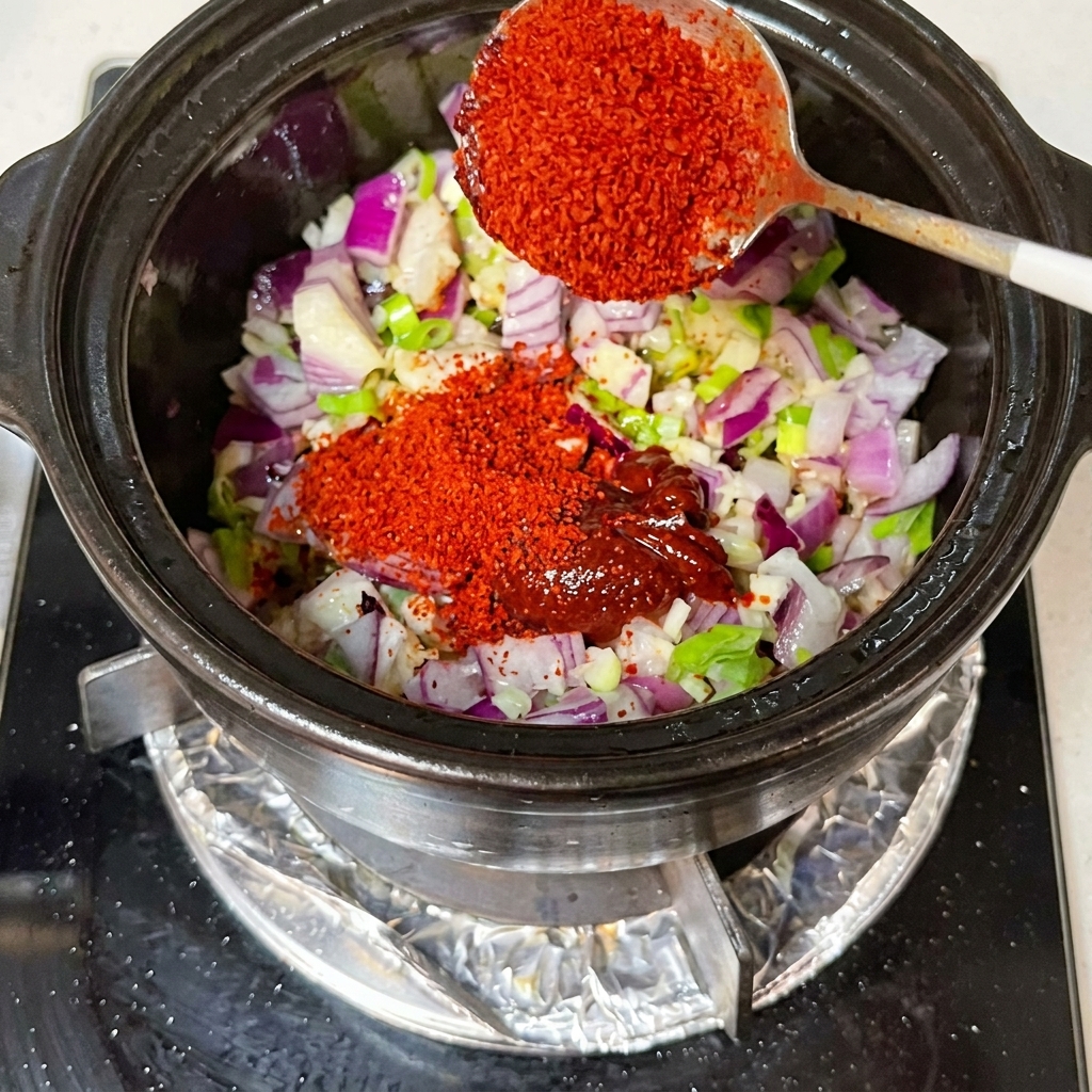 Salsa di soia e kimchi mescolati in un tegame con cipolle a cubetti e aromi.