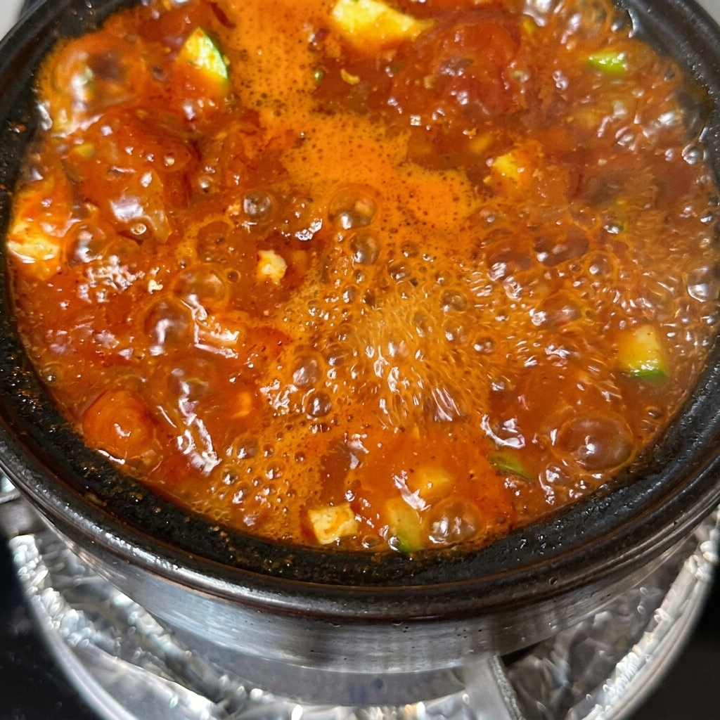 Un tegame finito di zuppa di tofu guarnito con cipollotti affettati e peperoncini rossi.