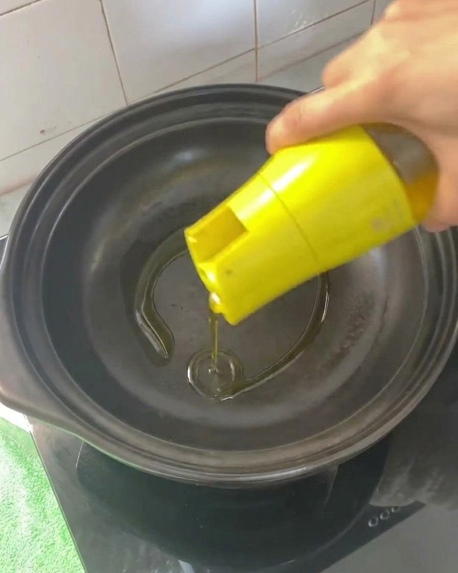 Olio da cucina versato in una pentola di coccio vuota e riscaldata.