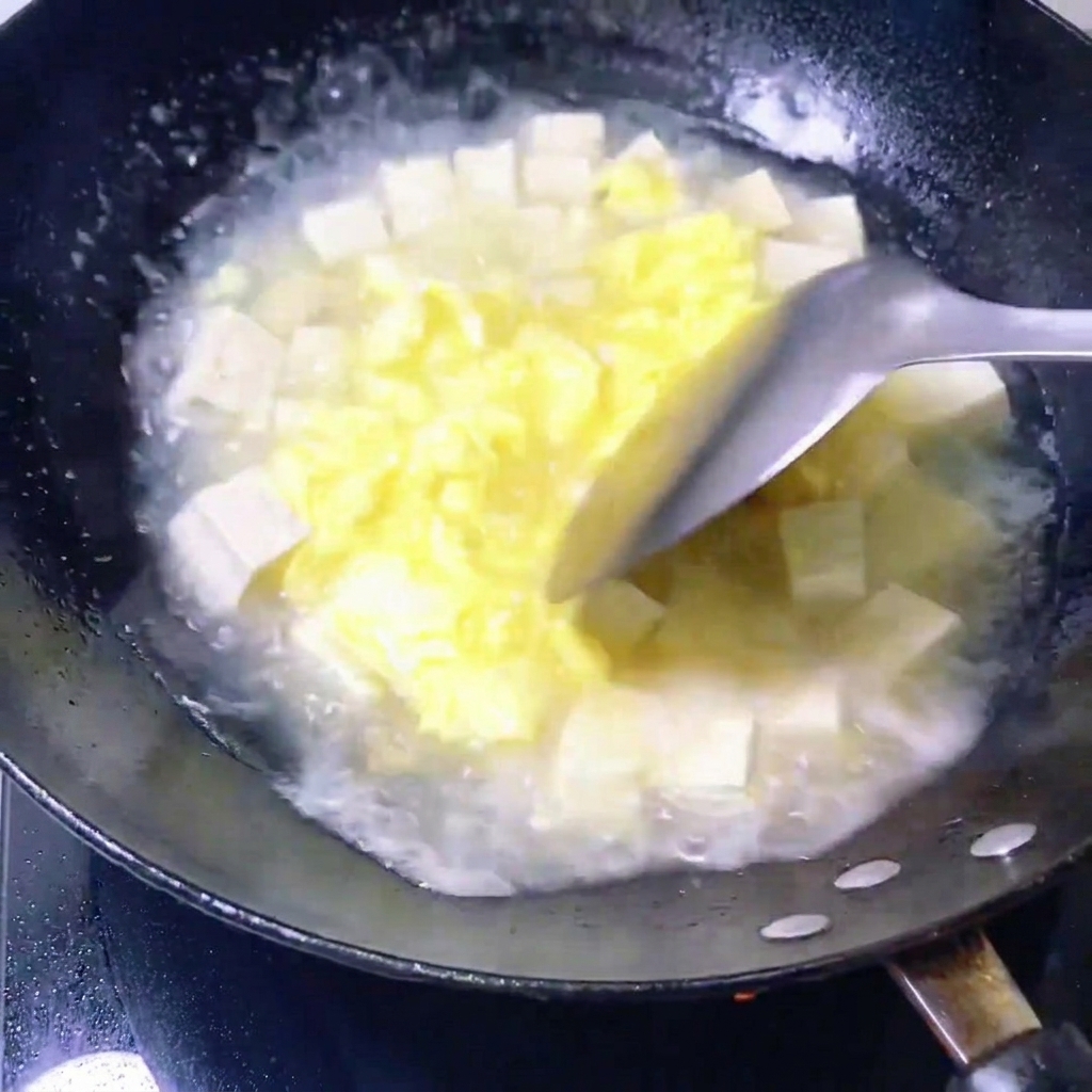Vongole fresche messe in una padella contenente il brodo di uova e tofu.