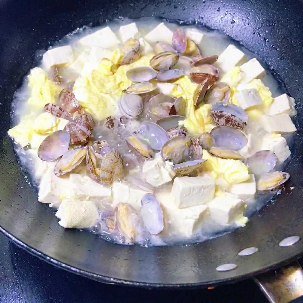 Verdure a foglia verde aggiunte alla zuppa di vongole, tofu e uova.