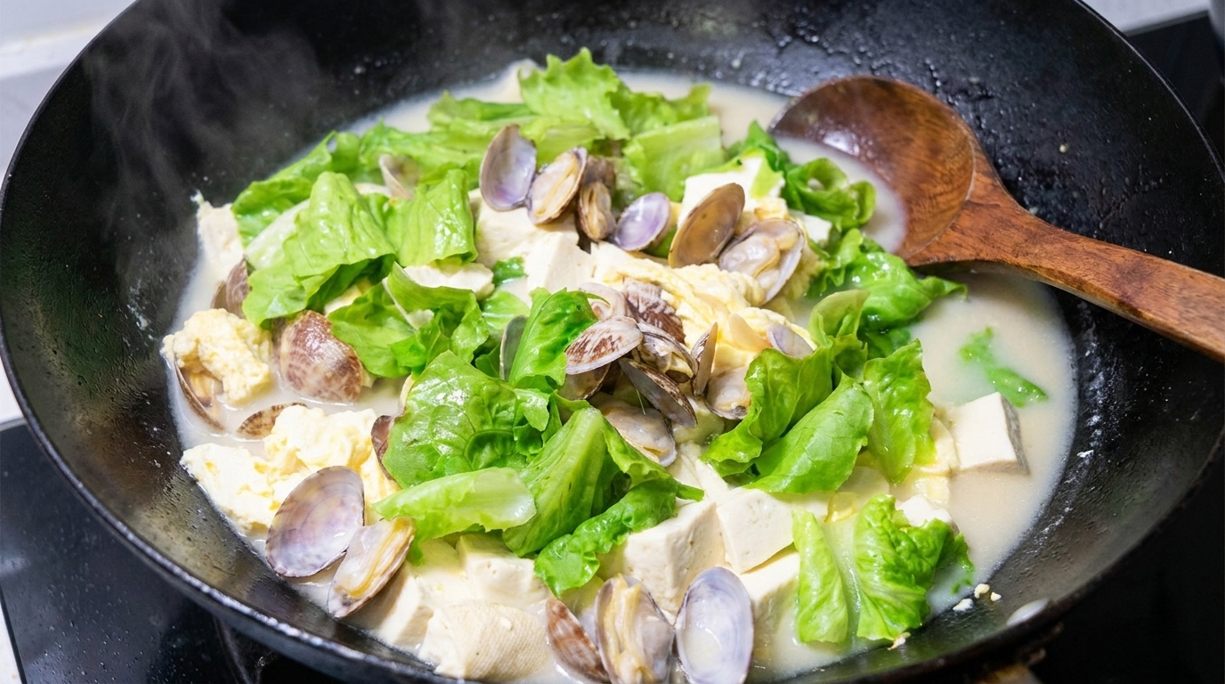 Una pentola fumante di zuppa di vongole e tofu, con un brodo cremoso a base di uova, tofu morbido e vongole fresche.