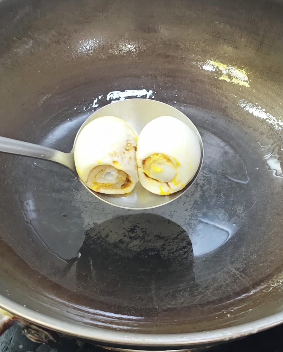 Due uova danatra salate che sfrigolano in un wok caldo con olio.