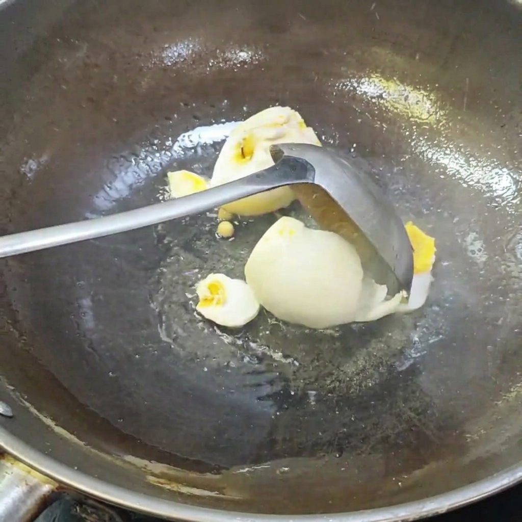 Un mestolo che rompe le uova danatra salate allinterno di un wok.