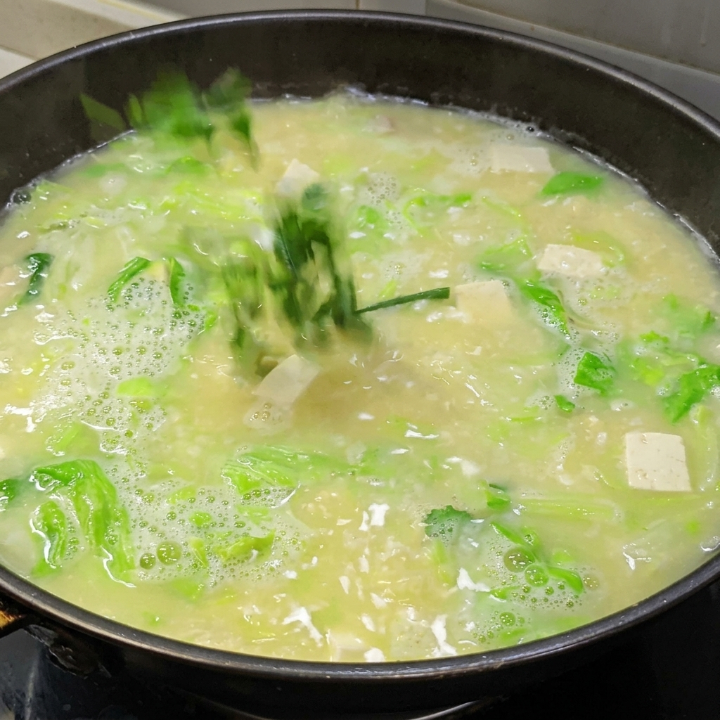 Una miscela di acqua e amido versata in una pentola di zuppa di uova salate e tofu per addensare il brodo.