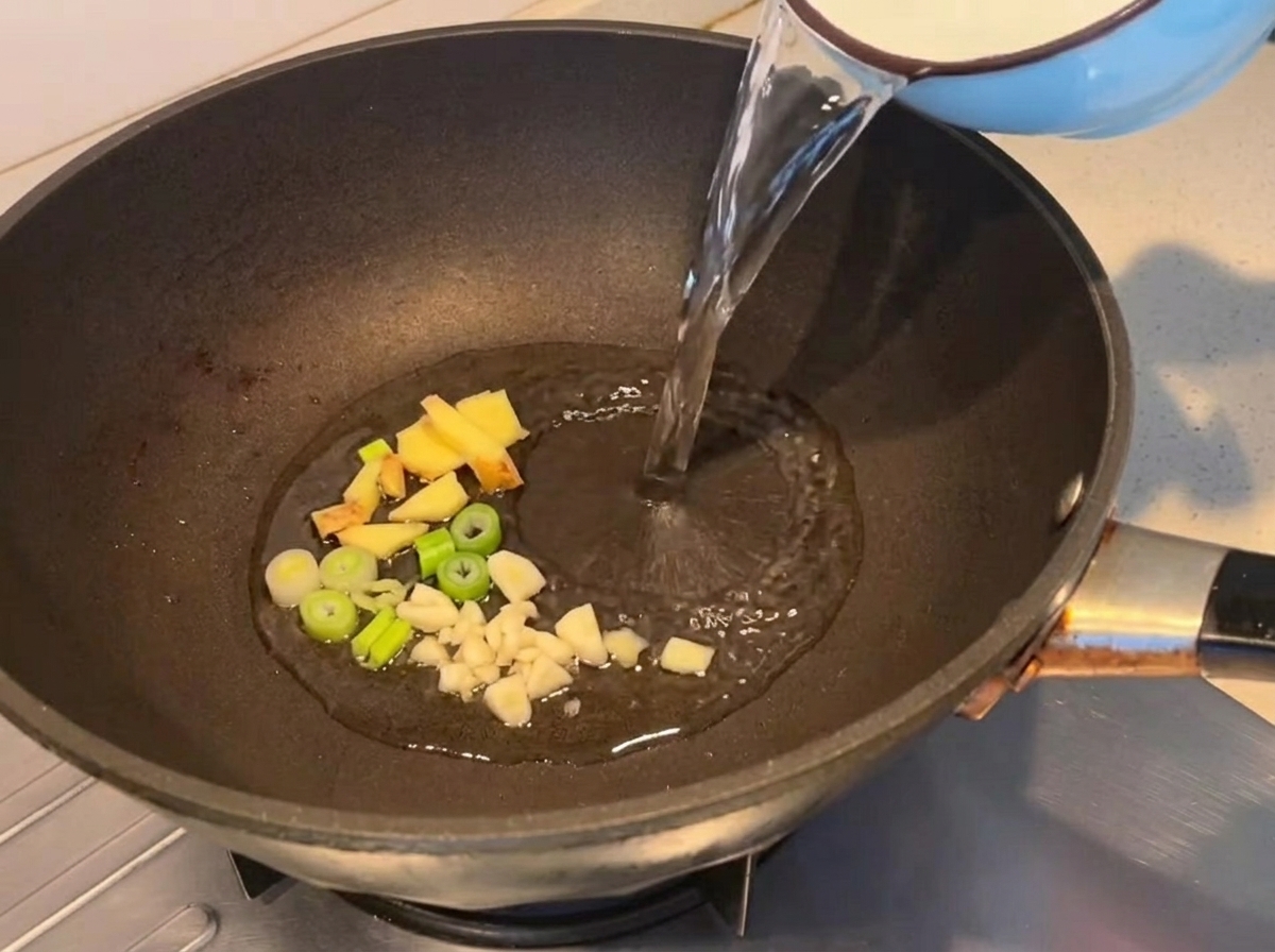 Acqua versata in una padella con aromi soffritti.