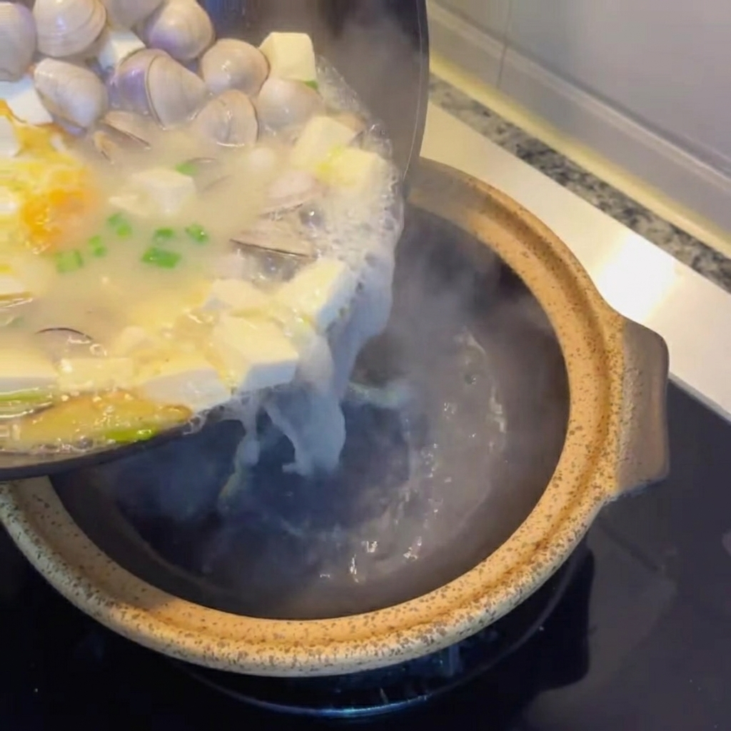 Zuppa di tofu e vongole versata in una pignatta di coccio.