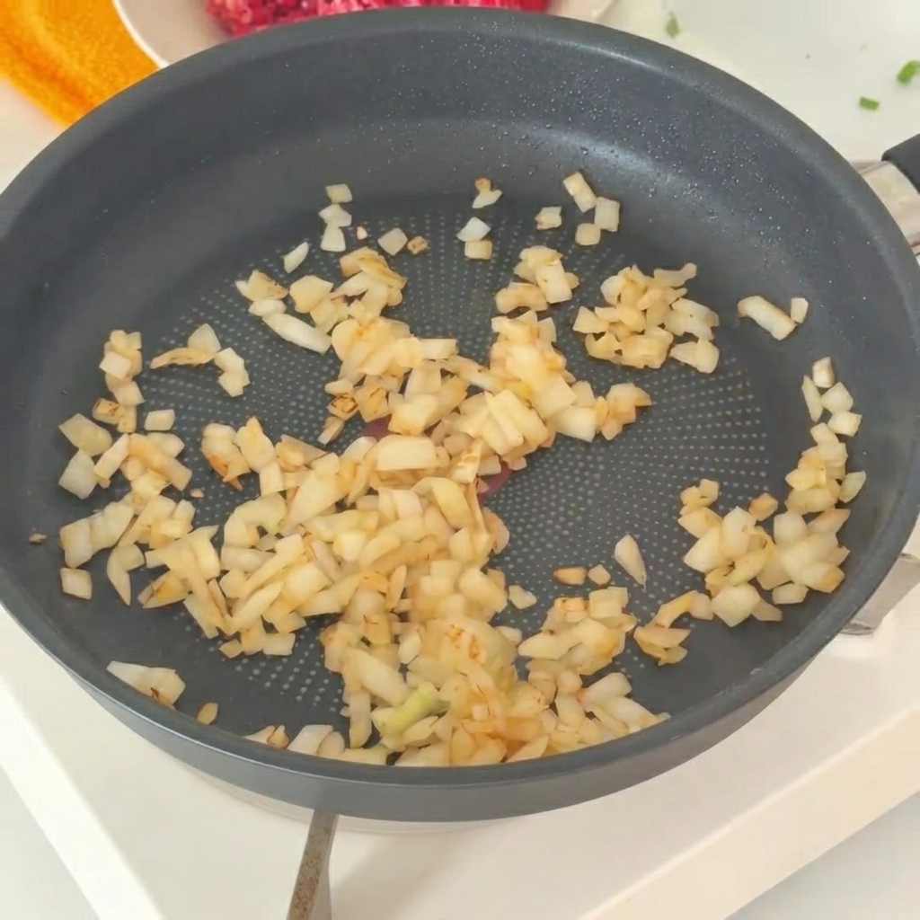 Cipolle soffritte trasferite in una ciotola con carne di manzo cruda.