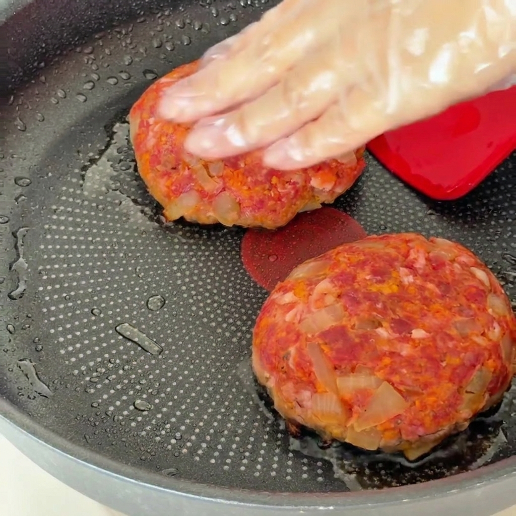Hamburger in padella coperti con un coperchio dopo essere stati girati.