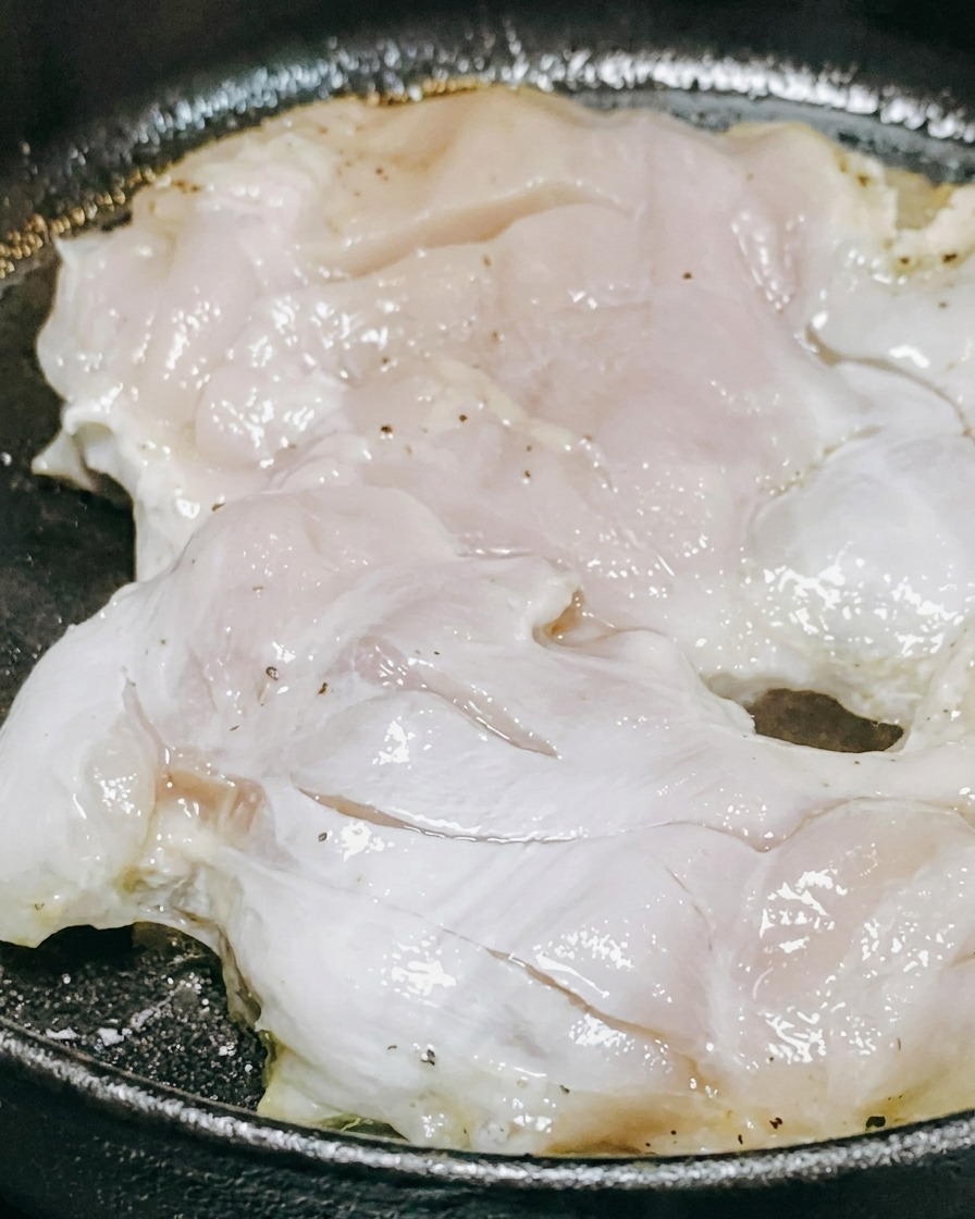 Salsa teriyaki e vino bianco versati sopra pezzi di pollo che cuociono in una padella.