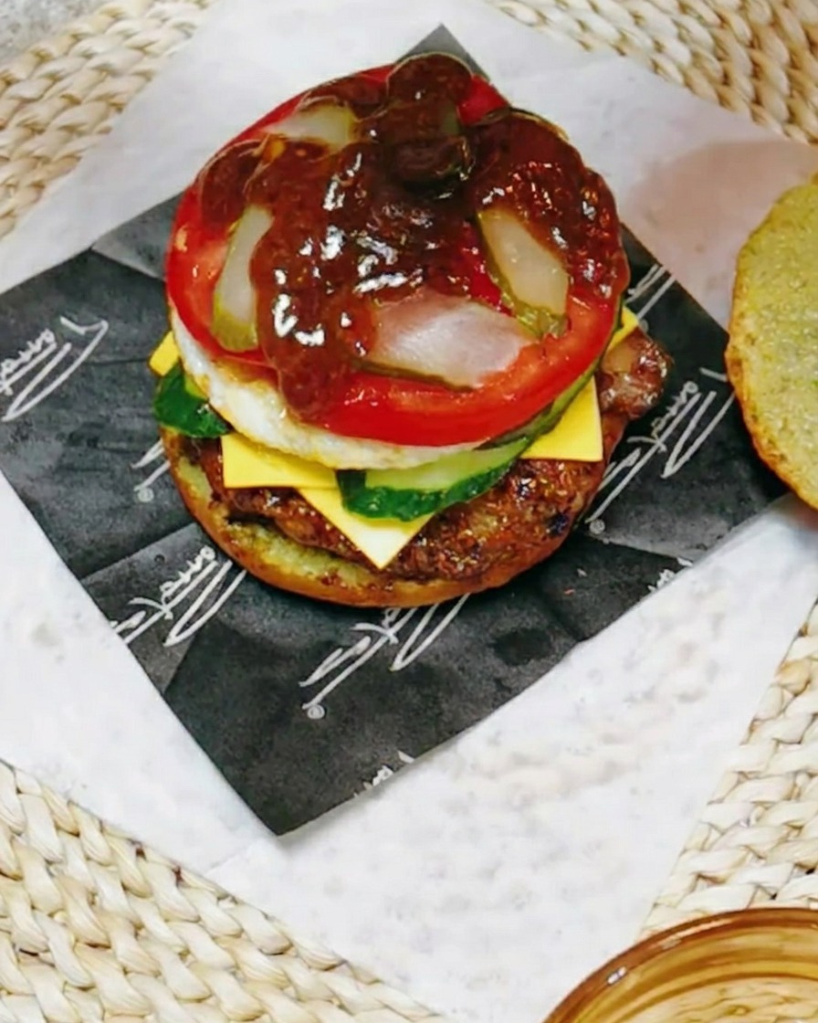 Un primo piano della pila del burger che viene guarnita con una salsa scura e saporita a base di teriyaki mescolata con succo di limone.