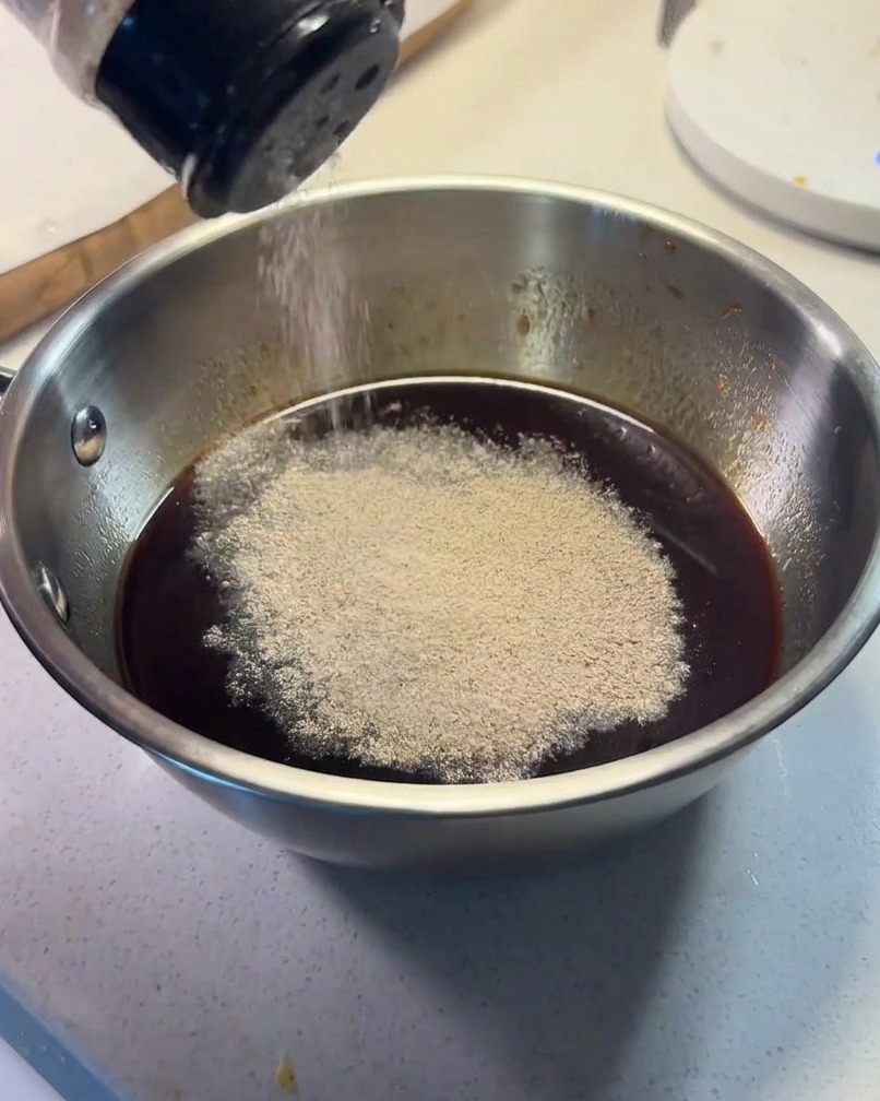 Ingredienti della salsa mescolati in una piccola ciotola di metallo con pepe nero spolverato sopra.