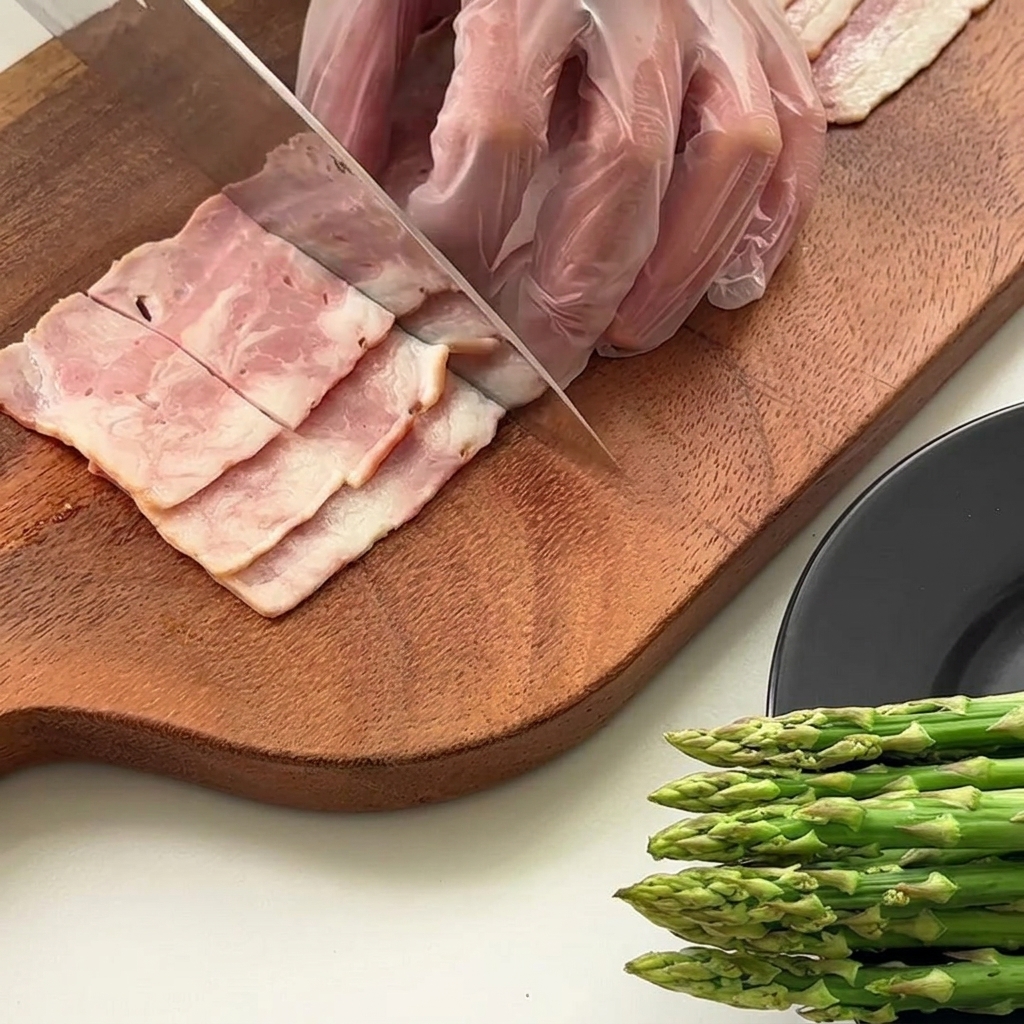 Steli di asparagi tagliati in lunghezze uguali su un tagliere di legno.