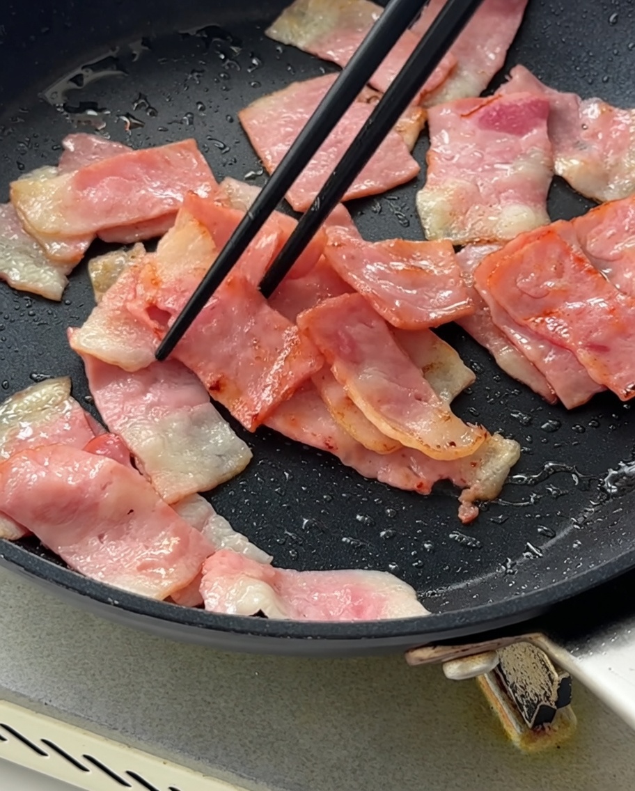 Cipolle rosse a cubetti aggiunte nella padella con la pancetta rosolata.