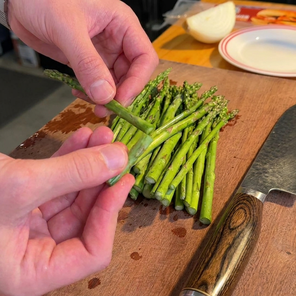 Asparagi freschi su un tagliere in legno, privati della parte legnosa e tagliati a pezzetti.