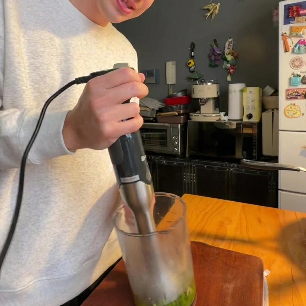 Un frullatore a immersione che riduce in crema gli asparagi e la cipolla cotti.