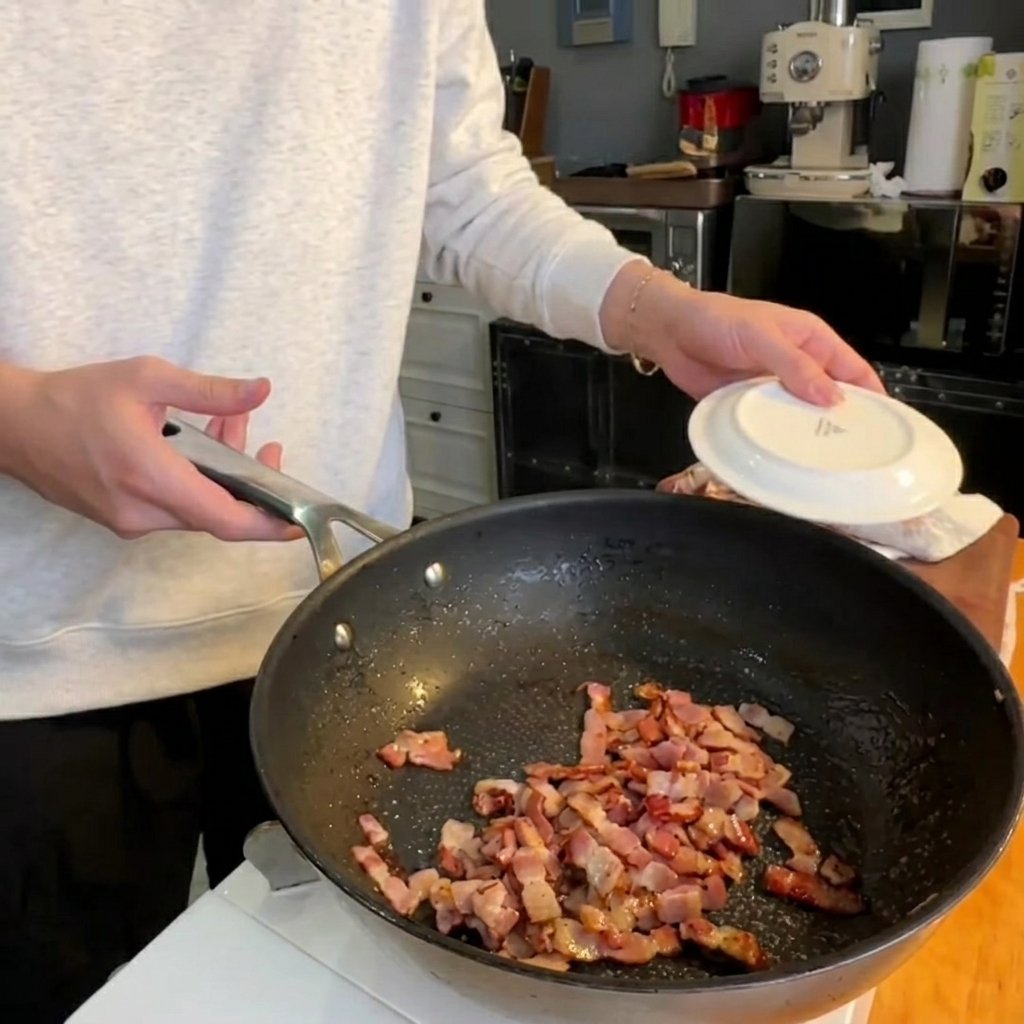 Punte di asparagi che saltano in padella insieme alla pancetta croccante.