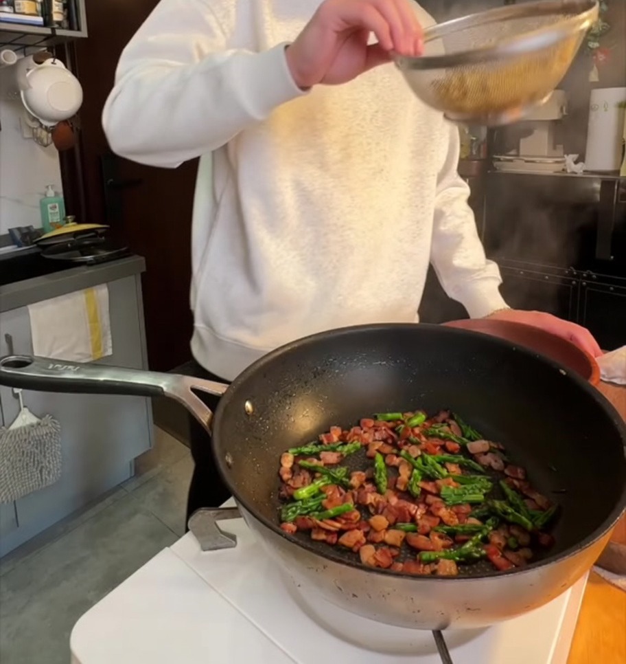 Penne bollite versate in padella con la pancetta e le punte di asparagi.