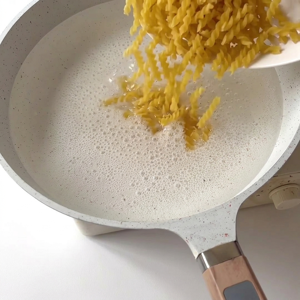 Fusilli che cadono in una pentola di acqua bollente.