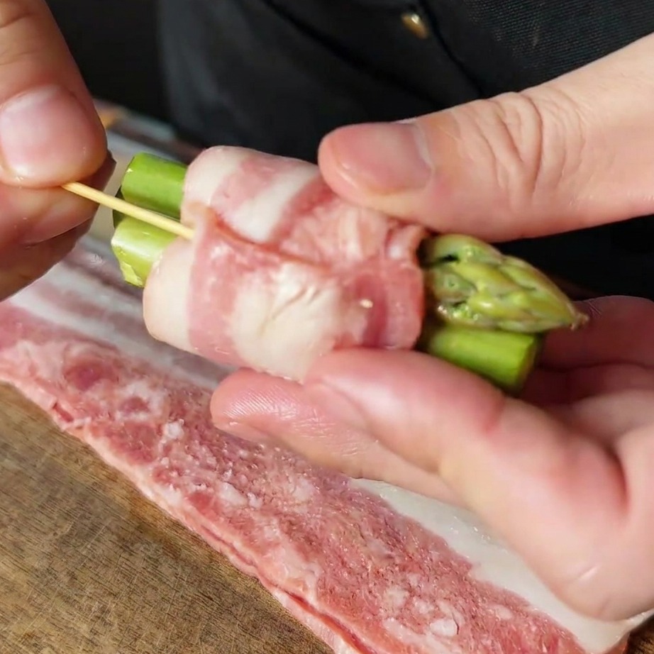 Un involtino di asparagi e pancetta fissato con uno stuzzicadenti di legno.