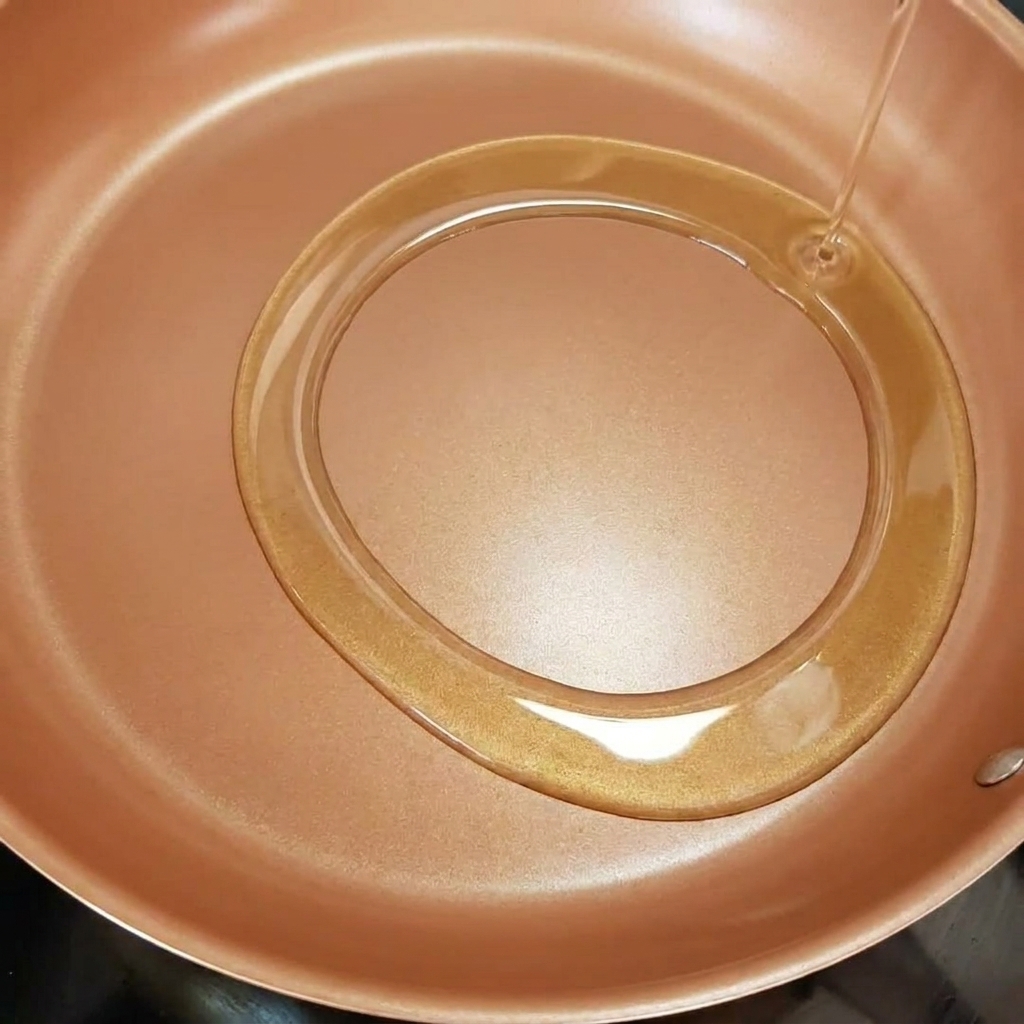 Strisce di cipolla che friggono in padella con olio doliva caldo.