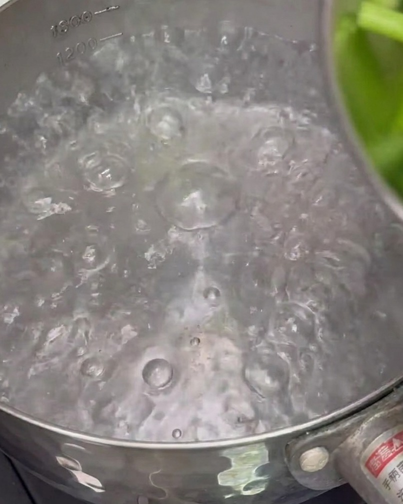 Pezzi di asparagi che bollono in una pentola dacqua per essere sbollentati.