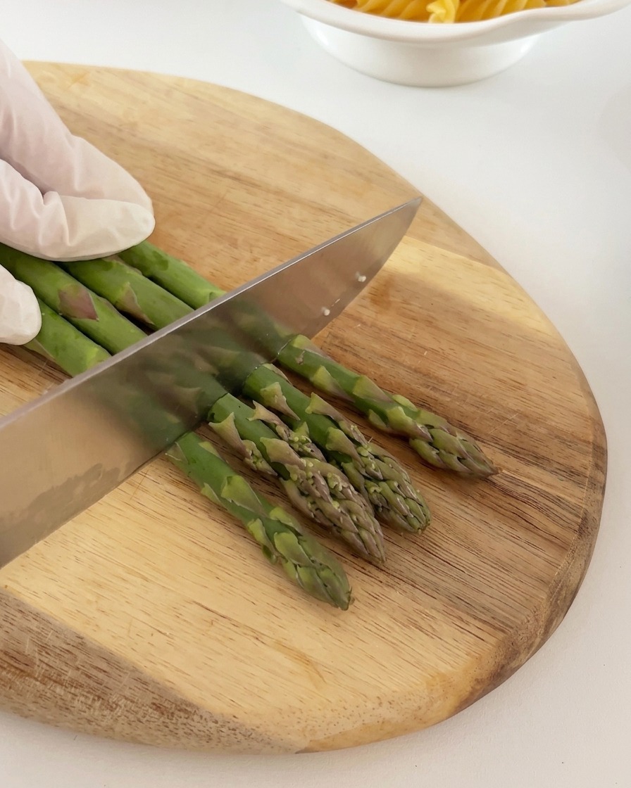 Mazzi di asparagi freschi tagliati ordinatamente in sezioni uguali su un tagliere di legno.