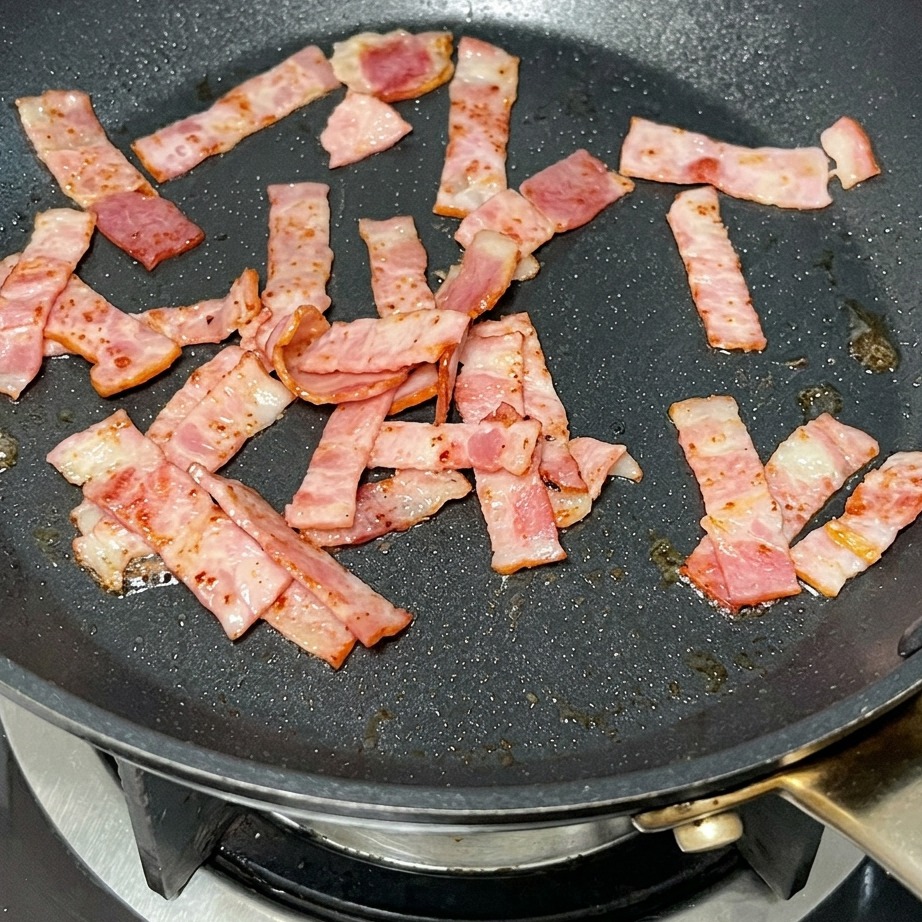 Una noce di burro che si scioglie in padella insieme ai pezzetti di pancetta croccante.