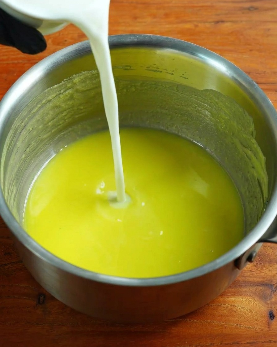 Latte caldo versato sulla base di roux mentre si mescola con la frusta.