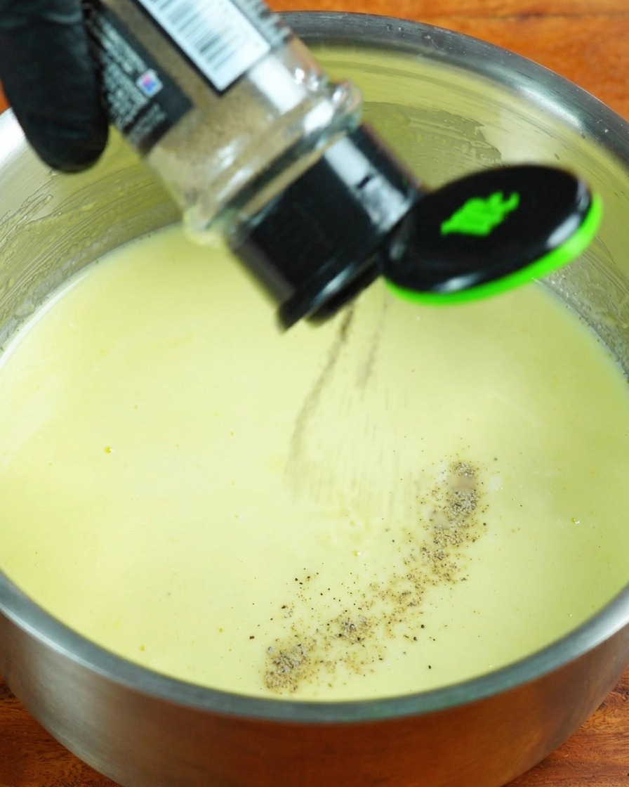 Panna, pepe bianco e sale aggiunti alla salsa di latte in cottura.